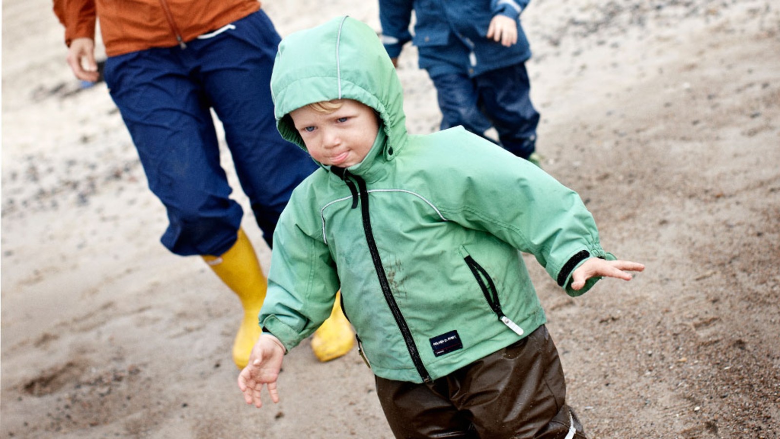 Familie på strand i regntøj